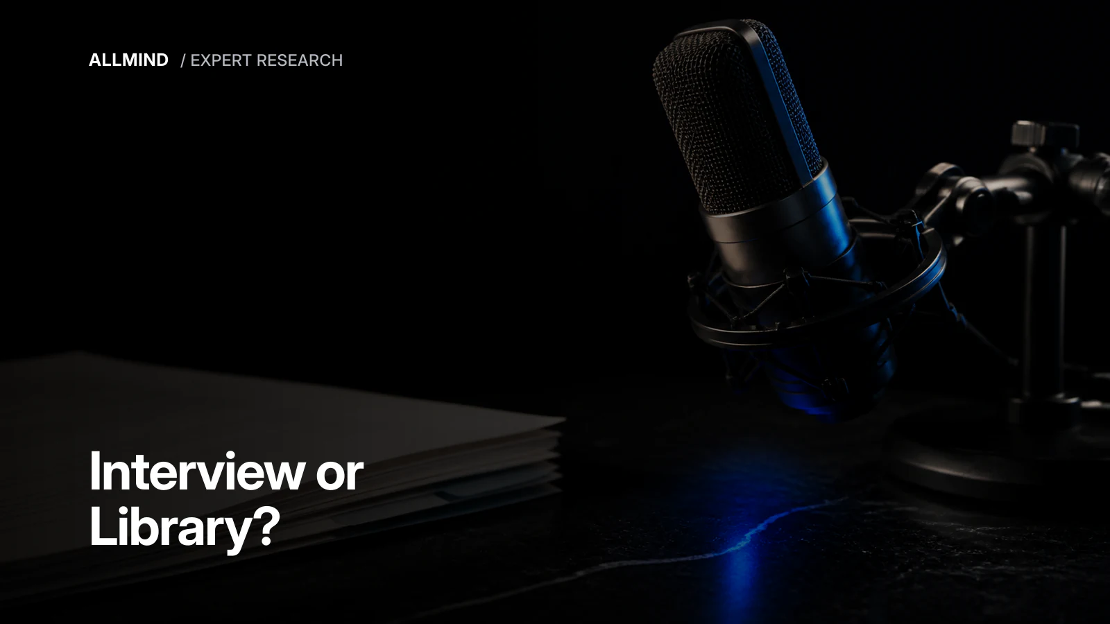 A studio microphone beside a stack of papers, illustrating the choice between a new interview and existing transcripts.